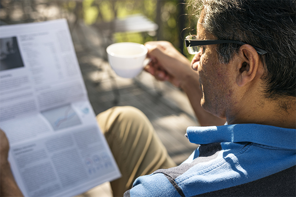 Man wearing glasses and reading the newspaper